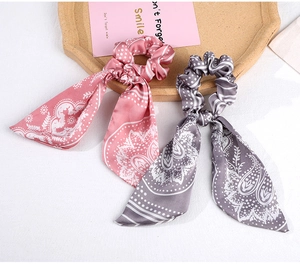 Detail of silk hair scrunchies with long ribbons and paisley patterns in pink and grey