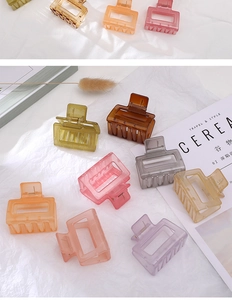 Collection of matte square hair claws in assorted pastel colors on a textured white surface