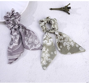 Close-up of vintage bow scrunchies with long streamers in purple and green paisley silk