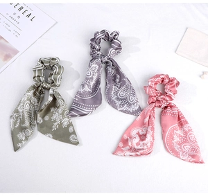 Three silk-satin scrunchies with long ribbons and white paisley floral patterns