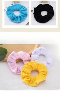 Detailed texture of multi-colored towel cloth scrunchies in blue, black, pink, and yellow