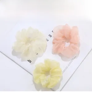 Détail de trois chouchous en organza translucide aux tons jaune pastel et rose tendre