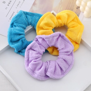 Three colorful microfiber scrunchies in blue, yellow, and purple on a white tray