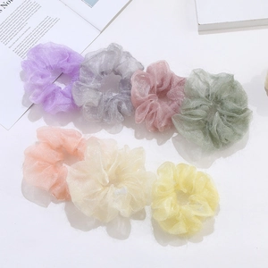 Lot de 7 chouchous en tulle brillant aux tons pastels sur une surface blanche