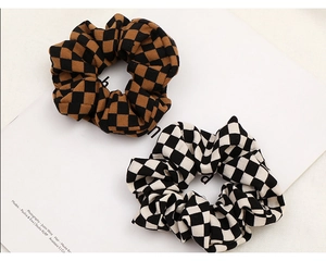 Detail view of brown and white checkered scrunchies on a minimalist magazine background