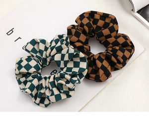 Close-up of green and brown checkerboard pattern fabric hair scrunchies on a magazine