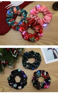 Detailansicht der LED-Weihnachtshaargummis aus Satin mit festlichen Mustern auf Holz