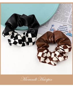 Detail of checkerboard patchwork scrunchies in black and coffee on a blue plate