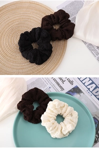 Gros plan de chouchous en tricot plissé en noir, marron foncé et beige crème