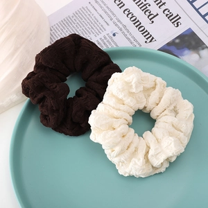 Lot de chouchous plissés à la mode de couleur marron et beige sur un plateau en céramique