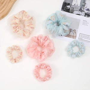 Flat lay of macaron floral mesh scrunchies in yellow, pink and blue shades