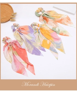 Close-up of four Morandi watercolor scrunchies with long ribbons on a wooden tray