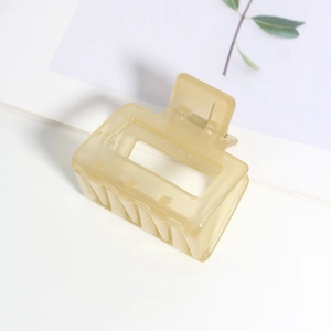 Détail d'une pince à cheveux carrée mate beige sur une carte florale décorative