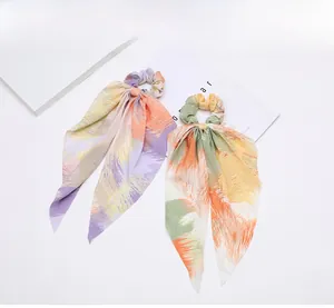 Detail view of two bohemian print hair scrunchies with long ribbons on a white background