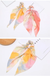 Detail of two colorful chiffon scrunchies with long ribbons and vibrant oil painting prints