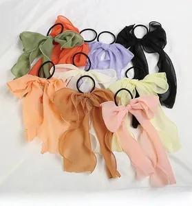 Detailed view of assorted colorful chiffon bow hair ties on a soft white fabric background