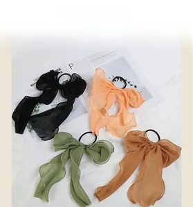 Flat lay detail of chiffon bow hair ties in black, pink, green, and caramel colors
