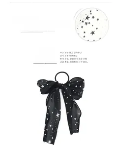 Detail of soft chiffon fabric featuring white star patterns on a large black hair bow