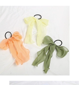 Detail view of colorful chiffon bow hair scrunchies in peach, yellow and green