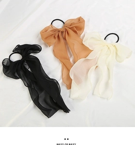 Detail of chiffon bow hair ties in black, yellow, and beige with long ribbon streamers