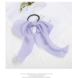 Detailed close-up of a purple chiffon bow hair scrunchie with light pleated texture