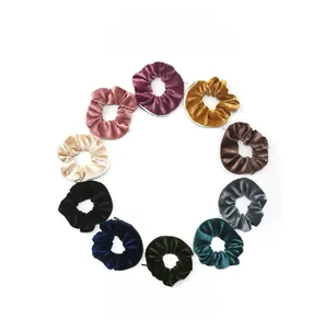 Set of 10 solid color velvet hair scrunchies in various shades on a white background