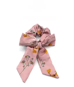 Detailed view of a pink floral hair scrunchie with long ribbons and a bow design