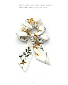 Detailed texture of white scrunchie with yellow floral print and long bow ribbon