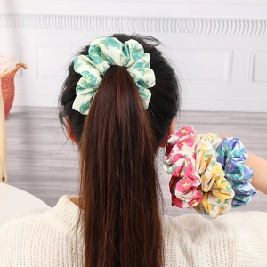 Floral print scrunchies in pastel colors for ponytails shown on a model wrist and hair