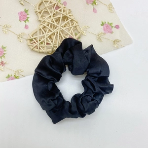 Gros plan d'un chouchou en satin noir avec texture lisse et bande élastique interne