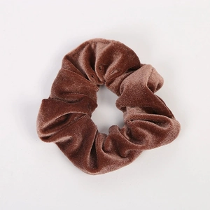 Gros plan détaillé montrant la texture du chouchou en velours marron sur fond blanc