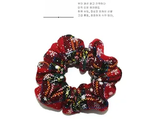 Dettaglio dell'elastico scrunchie in maglia a quadri rossi e neri con fiocchi di neve