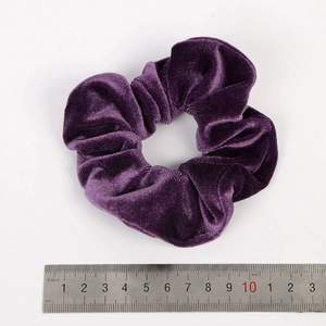 Vue macro d'un chouchou en velours violet foncé de 10cm avec texture et échelle de mesure
