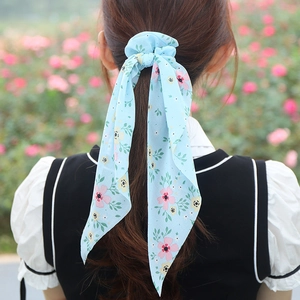 Floral print chiffon scrunchie with long ribbons worn by a model in a garden