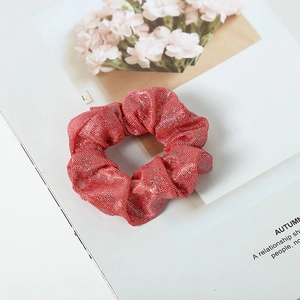 Detail of red glitter fabric scrunchie on a magazine with pink carnation accents