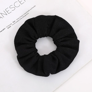 Classic black scrunchie with grainy corn kernel texture on white magazine background