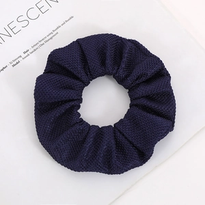 Detail of navy blue scrunchie with corn grain texture fabric on magazine background