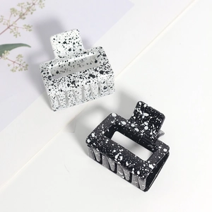Détail de pinces à cheveux carrées à motif dalmatien noir et blanc avec finition brillante