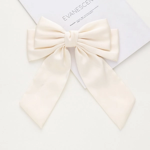 Détail de la pince à cheveux nœud en satin crème avec de longs rubans élégants de style