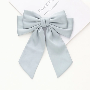 Détail d'une grande barrette à nœud bleu gris avec de longs rubans élégants sur fond blanc