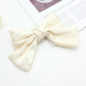 Détail d'une barrette nœud en satin crème élégante ornée de strass argentés brillants