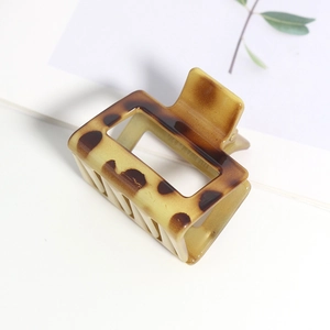 Détail d'une pince à cheveux carrée en écaille de tortue avec motif léopard sur fond blanc