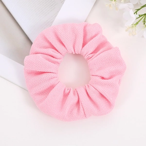 Close-up of pink textured knit hair scrunchie with soft ruffled fabric and elastic band