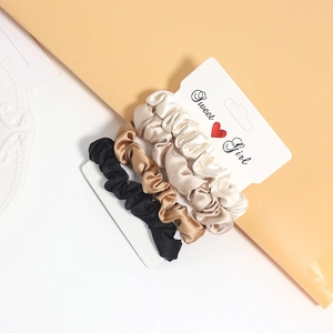 Set of four satin silk scrunchies in black, coffee, champagne and cream on a display card