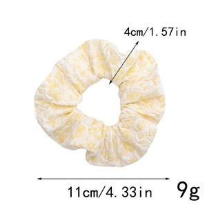 Detailed view of yellow floral scrunchie with 11cm outer diameter and soft pleated texture