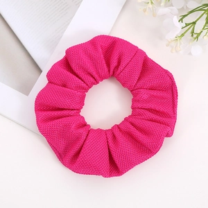 Detailed close-up of a vibrant fuchsia scrunchie with textured corn grain woven fabric