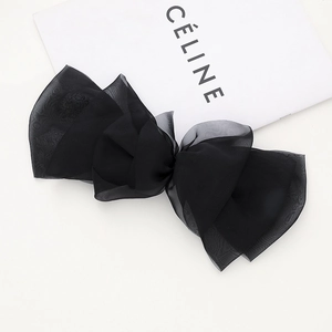 Gros plan sur un grand nœud papillon en dentelle et organza noir sur fond blanc épuré