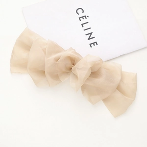 Vue détaillée d'une grande pince à cheveux nœud en tulle beige avec bords ondulés