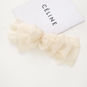 Détail d'une grande pince à cheveux en organza beige avec des couches de tissu voilé