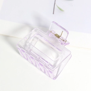Détail d'une pince à cheveux rectangulaire violette mate avec un ressort en métal doré